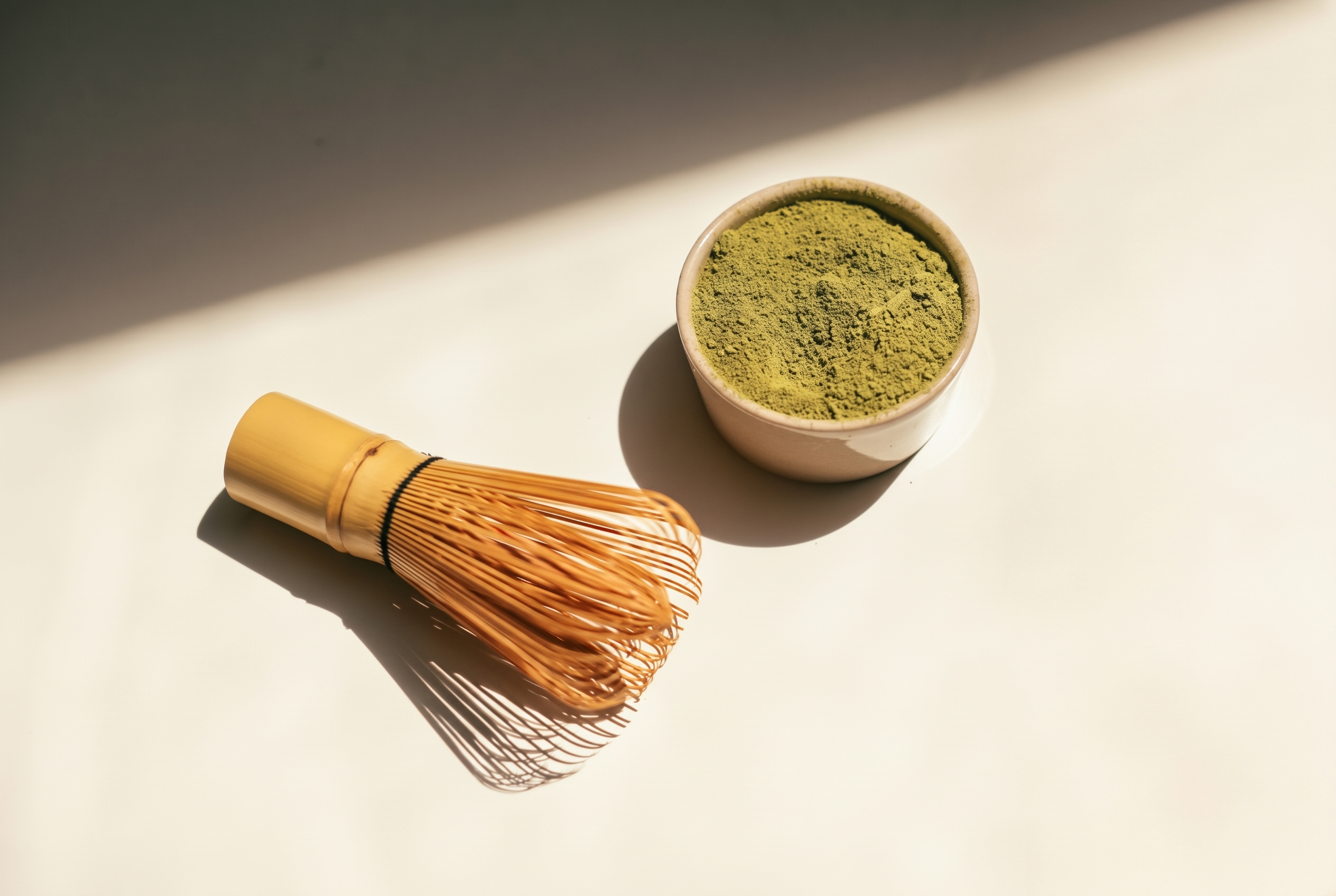 Cuenco de matcha y batidor de bambú sobre fondo cálido